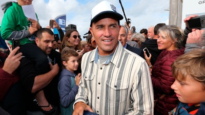 In this Oct. 9, 2019, file photo, surfer Kelly Slater is surrounded by fans after he leaves his footprint cement slab at Anglet Surf Avenue, in Anglet, southwestern France. Kelly Slater is planning to build the world's largest man-made wave in the desert. Plans for Coral Mountain will feature the largest, rideable, open-barrel human-made wave in the world with technology from Kelly Slater Wave Company, a division of the World Surf League. The wave basin will be part of a 400-acre site in La Quinta, California, set at the base of Coral Mountain.