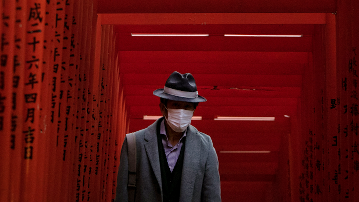 A man with a mask walk through torii gates at the Hie Shrine In Tokyo, Sunday, March 1, 2020. The coronavirus has claimed its first victim in the United States as the number of cases shot up in Iran, Italy and South Korea and the spreading outbreak shook the global economy.