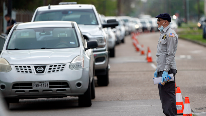 A man tries to talk to officials while standing in front of a line of cars stretching over two-miles to enter drive-thru testing for COVID-19 at United Memorial Medical Center, Thursday, March 19, 2020, in Houston. For most people, the coronavirus causes only mild or moderate symptoms, such as fever and cough. For some, especially older adults and people with existing health problems, it can cause more severe illness, including pneumonia.