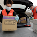 Volunteers Keshia Link, left, and Dan Peterson unload boxes of donated gloves and alcohol wipes from a car at a drive-up donation site for medical supplies at the University of Washington to help fight the coronavirus outbreak Tuesday, March 24, 2020, in Seattle.