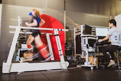 Graduate student Delaney Miller runs on a treadmill aided by the ankle exoskeleton emulator. Fellow graduate student Guan Rong Tan controls the emulator and monitors Miller's gait and respiration.