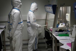 French lab scientists in hazmat gear inserting liquid in test tube manipulate potentially infected patient samples at Pasteur Institute in Paris, Thursday, Feb. 6, 2020.