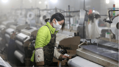In this Feb. 27, 2020 photo, a woman works on a spinning mill in a textile factory in Hangzhou in eastern China's Zhejiang Province. A gauge of Chinese manufacturing plunged in February by an even wider margin than expected after efforts to contain a virus outbreak shut down much of the world's second-largest economy.