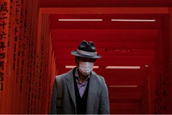 A man with a mask walk through torii gates at the Hie Shrine In Tokyo, Sunday, March 1, 2020. The coronavirus has claimed its first victim in the United States as the number of cases shot up in Iran, Italy and South Korea and the spreading outbreak shook the global economy.