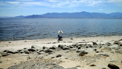 In this April 30, 2015 file photo, a man fishes along the receding banks of the Salton Sea near Bombay Beach, Calif. Scientists say that half of the world's sandy beached are at risk of disappearing by the end of the century if climate changes continues unchecked. Researchers at the European Union's Joint Research Center in Ispra, Italy, used satellite images to track the way beaches changed over the past 30 years and project how global warming might affect them in the future.