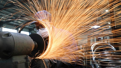 In this Monday, March 2, 2020, photo, a worker wearing a mask works at a factory producing bicycle wheel rims in Hangzhou in eastern China's Zhejiang province. Factories in China that make the world's smartphones, toys and other consumer goods are trying to protect their employees from a virus outbreak as they resume production. Manufacturers are buying masks by the thousands and jugs of disinfectant. The ruling Communist Party has told local officials to help reopen factories that were idled by the most intensive anti-disease controls ever imposed.