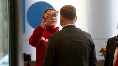 Austrian rescue personnel checks the body temperature of a man during an informal meeting of oil ministers of the Organization of Petroleum Exporting Countries, OPEC, at the OPEC headquarters in Vienna, Austria, Wednesday, March 4, 2020.