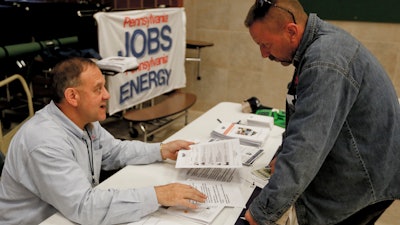 In this Nov. 2, 2017, photo, a recruiter in the shale gas industry, left, speaks with an attendee of a job fair in Cheswick, Pa.