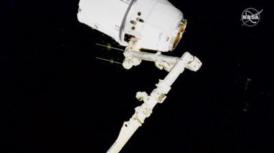 In this image taken from NASA video, NASA astronauts Andrew Morgan and Jessica Meir use the International Space Station's robot arm to capture the Dragon capsule Monday, March 9, 2020.