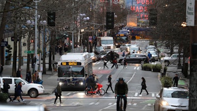 In this March 6, 2020 photo, bus, bike, pedestrian and car traffic is light on Pike St. in downtown Seattle at 5:20 pm during the Friday evening commute.