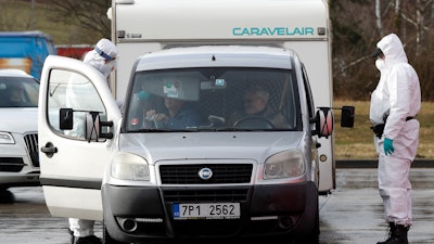 A member of the medical staff measures the temperature of a traveller at the border crossing with Germany in Rozvadov, Czech Republic, Monday, March 9, 2020. Czech authorities started on Monday random checks of arriving vehicles at the border crossings with Austria, Germany and Slovakia in reaction to the outbreak of the new coronavirus in Europe, particularly in Italy. As part of the move, officials measure the temperatures of some passengers in cars, trucks and buses.