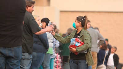 In this Nov. 17, 2018, file photo, a California Office of Emergency Services worker hands out bottles of water to Camp Fire evacuees waiting in line at the Chico FEMA station in Chico, Calif.