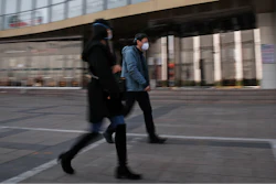 People wearing protective face masks walk by a quiet Silk Street Mall, a usually popular tourist spot before the new coronavirus outbreak in Beijing, Wednesday, March 11, 2020.