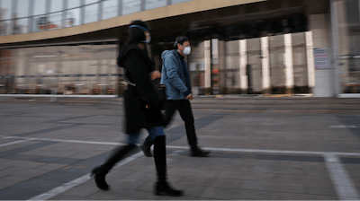 People wearing protective face masks walk by a quiet Silk Street Mall, a usually popular tourist spot before the new coronavirus outbreak in Beijing, Wednesday, March 11, 2020.