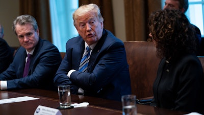 Bank of America CEO Brian Moynihan, left, and CEO of the Independent Community Bankers of America Rebeca Romero Rainey, right, listen as President Donald Trump speaks during a meeting with banking industry executives about the coronavirus at the White House, March 11, 2020.