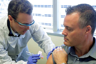 Pharmacist Michael Witte, left, gives Neal Browning a shot in the first-stage study of a potential coronavirus vaccine Monday, March 16, 2020, at the Kaiser Permanente Washington Health Research Institute in Seattle. Browning is the second patient to receive the shot in the study.
