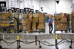 In this March 23, 2018 file photo, associates move bins filled with products at the loading dock of Amazon's then-new fulfillment center in Livonia, MI.