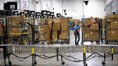 In this March 23, 2018 file photo, associates move bins filled with products at the loading dock of Amazon's then-new fulfillment center in Livonia, MI.