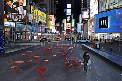 A woman walks through a lightly trafficked Times Square in New York, Monday, March 16, 2020. Bars and restaurants will become takeout-only and businesses from movie theaters and casinos to gyms and beyond will be shuttered Monday night throughout New York, New Jersey and Connecticut because of the coronavirus, the states' governors said.