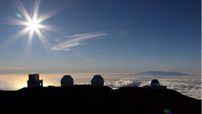 In this July 14, 2019, file photo, the sun sets behind telescopes at the summit of Mauna Kea in Hawaii. The cost to build a giant telescope that's unpopular among many Native Hawaiians is now estimated to have ballooned by a billion dollars. 'While an exact updated project cost will depend on when and where on-site construction begins for the Thirty Meter Telescope, the latest estimate for the TMT project is in the range of $2.4 billion in 2020 dollars,' Gordon Squires, TMT vice president, said in a statement this week. Construction of one of the world's largest telescopes on Hawaii's tallest mountain, Mauna Kea, has been stalled by foes of the embattled project who say the telescope will desecrate land held sacred to some Native Hawaiians.