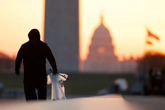 A National Park Service worker picks up trash along the drained Lincoln Memorial Reflecting Pool as the Washington Monument and the U.S. Capitol are seen in the distance in Washington, at sunrise Wednesday, March 18, 2020. The number of tourist is down ahead of an expected surge in coronavirus cases.
