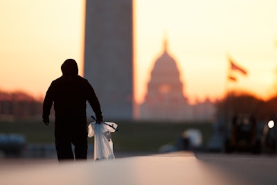 A National Park Service worker picks up trash along the drained Lincoln Memorial Reflecting Pool as the Washington Monument and the U.S. Capitol are seen in the distance in Washington, at sunrise Wednesday, March 18, 2020. The number of tourist is down ahead of an expected surge in coronavirus cases.