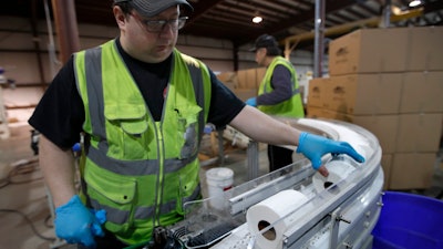 A worker guides toilet paper on a conveyor belt at the Tissue Plus factory, Wednesday, March 18, 2020, in Bangor, Maine. The new company has been unexpectedly busy because of the shortage of toilet paper brought on by hoarders concerned about the coronavirus.