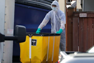 A member of a cleaning crew wheels a cart toward a vehicle at the Life Care Center, where at least 30 coronavirus deaths have been linked to the facility, Wednesday, March 18, 2020, in Kirkland, Wash. Staff members who worked while sick at multiple long-term care facilities contributed to the spread of COVID-19 among vulnerable elderly in the Seattle area, federal health officials said Wednesday.