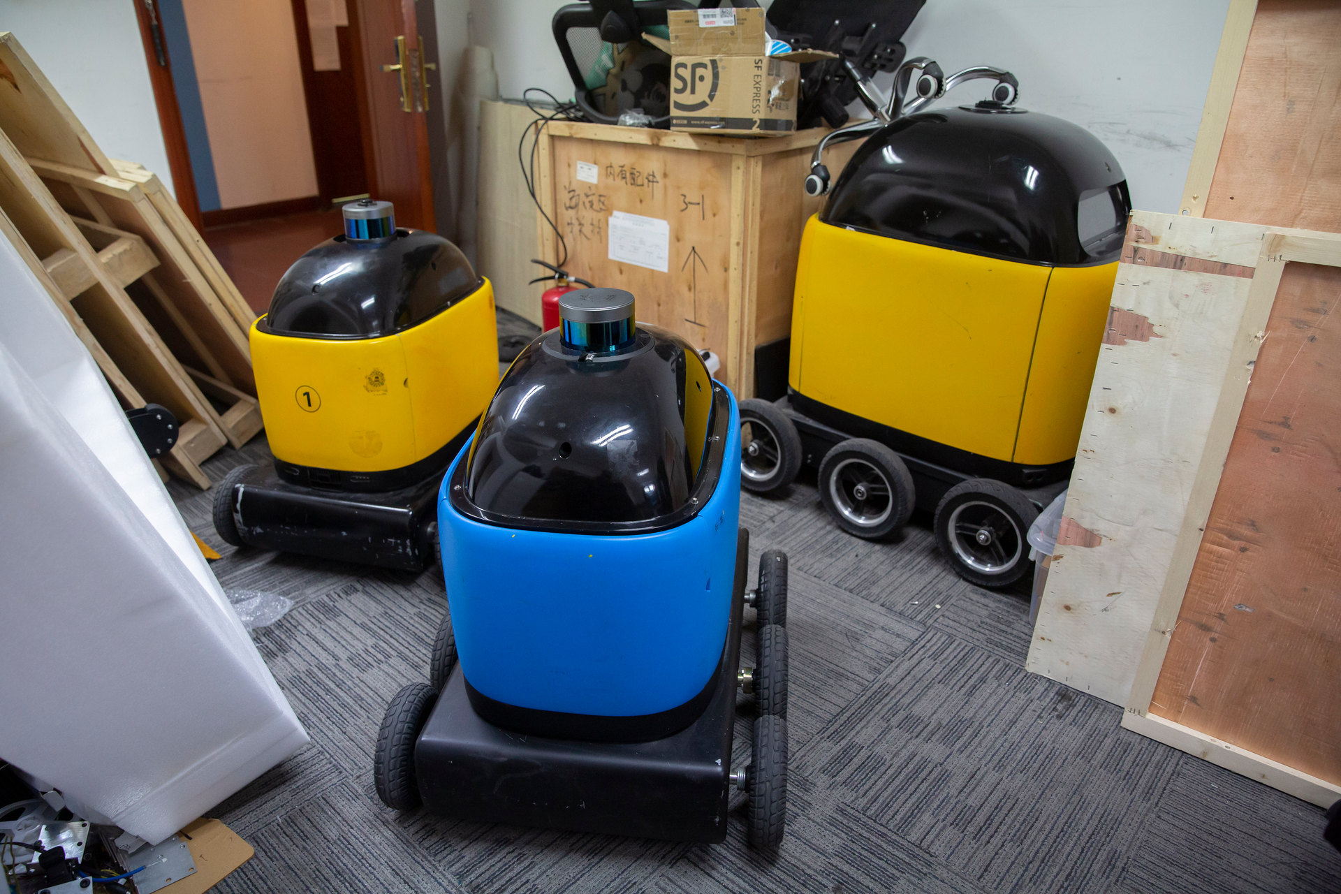 In this March 18, 2020, photo, robots are parked in a room at the offices of ZhenRobotics in Beijing. While other industries struggle, one robot maker says China's virus outbreak is boosting demand for his knee-high, bright yellow robots to deliver groceries and patrol malls for shoppers who fail to wear masks.