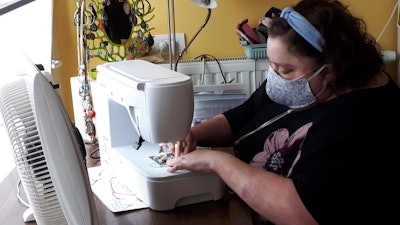 In this photo taken on Thursday, March 19, 2020, Sien Lagae, works on a mouth mask, meant to help protect from the spread of COVID-19, on her sewing machine at home in Torhout, Belgium.
