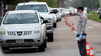 A man tries to talk to officials while standing in front of a line of cars stretching over two-miles to enter drive-thru testing for COVID-19 at United Memorial Medical Center, Thursday, March 19, 2020, in Houston. For most people, the coronavirus causes only mild or moderate symptoms, such as fever and cough. For some, especially older adults and people with existing health problems, it can cause more severe illness, including pneumonia.