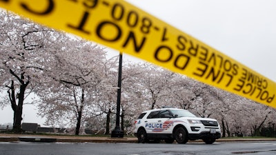 A Washington D.C. Metropolitan Police vehicle is parked on the other side of a tape police line along the Tidal Basin as cherry blossoms cover the trees, in Washington, Monday, March 23, 2020. As Washington, D.C. continues to work to mitigate the spread of the coronavirus (COVID-19), Mayor Muriel Bowser extended road closures and other measures to restrict access to the Tidal Basin, a main tourist attraction.