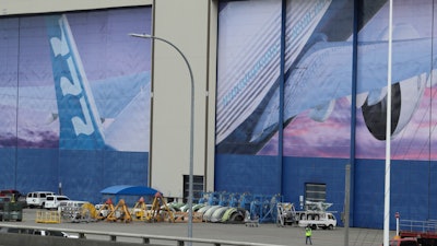 A worker walks near a mural of a Boeing 777 airplane at the company's manufacturing facility in Everett, Wash., March 23, 2020.