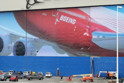 A worker walks near a mural of a Boeing 747-8 airplane at the company's manufacturing facility in Everett, Wash., Monday, March 23, 2020, north of Seattle.