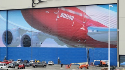 A worker walks near a mural of a Boeing 747-8 airplane at the company's manufacturing facility in Everett, Wash., Monday, March 23, 2020, north of Seattle.