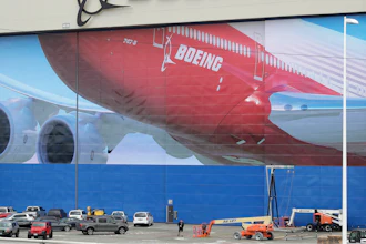 A worker walks near a mural of a Boeing 747-8 airplane at the company's manufacturing facility in Everett, Wash., Monday, March 23, 2020, north of Seattle.