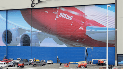 A worker walks near a mural of a Boeing 747-8 airplane at the company's manufacturing facility in Everett, Wash., Monday, March 23, 2020, north of Seattle.