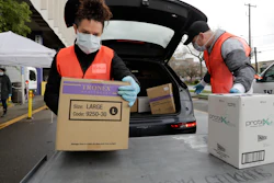 Volunteers Keshia Link, left, and Dan Peterson unload boxes of donated gloves and alcohol wipes from a car at a drive-up donation site for medical supplies at the University of Washington to help fight the coronavirus outbreak Tuesday, March 24, 2020, in Seattle.