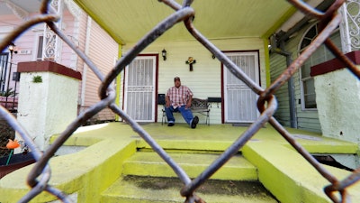 In this March 24, 2020, photo, David McGraw poses for a portrait as he sits on his front porch in New Orleans. Barely a week ago, McGraw was cooking daily for hundreds of fine diners at one of New Orleans’ illustrious restaurants. Today, he’s cooking for himself, at home, laid off along with hundreds of thousands of people across the U.S. in a massive economic upheaval spurred by efforts to slow the spread of the coronavirus.