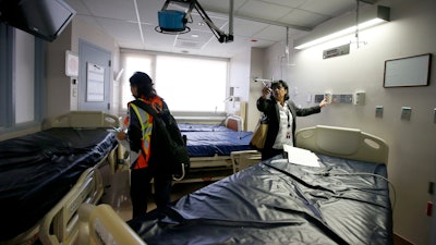 Susie McCann, right, of the Arizona health department, assess a room in the emergency area with a member of the U.S. Army Corps of Engineers as they tour the currently closed St. Luke's Medical Center hospital to see the viability of reopening the facility for possible future use due to the coronavirus Wednesday, March 25, 2020, in Phoenix.