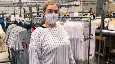 This image provided by Fanatics, shows a model wearing a protective mask and gown for medical professionals made from the fabric of a baseball uniform.