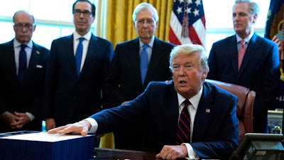 President Donald Trump speaks before he signs the coronavirus stimulus relief package in the Oval Office at the White House, Friday, March 27, 2020, in Washington. Listening are from left, Larry Kudlow, White House chief economic adviser, Treasury Secretary Steven Mnuchin, Senate Majority Leader Mitch McConnell, R-Ky., and House Minority Leader Kevin McCarty of Calif.
