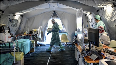 Medical personnel work inside one of the emergency structures that were set up to ease procedures outside the hospital of Brescia, Northern Italy, Tuesday, March 10, 2020.