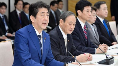 Japan's Prime Minister Shinzo Abe, left, speaks during a meeting on countermeasures against the new coronavirus infections at his official residence in Tokyo Tuesday, March 10, 2020.