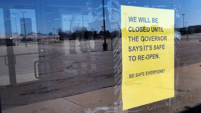 A closed sign is shown at Romeo & Juliet Furniture and Appliances with an empty parking lot in Detroit, Thursday, April 2, 2020.