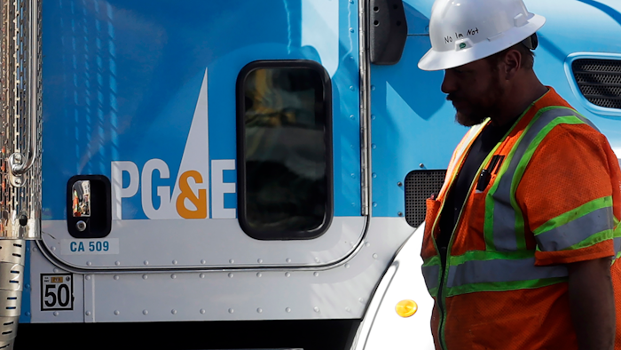 In this Aug. 15, 2019, file photo, a Pacific Gas & Electric worker walks in front of a truck in San Francisco.