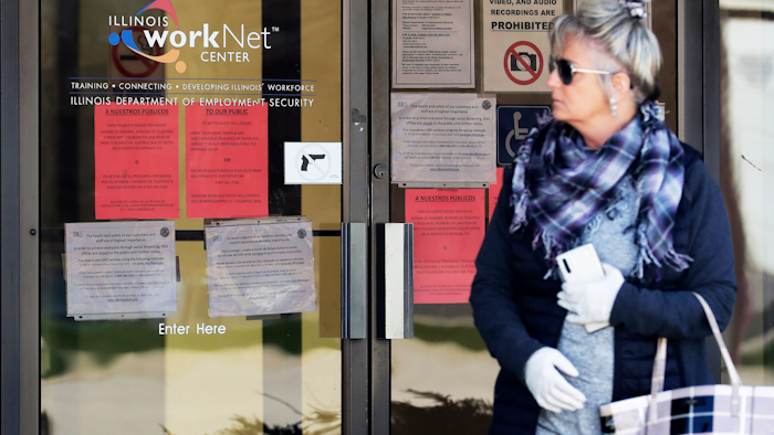 A woman looks to get information about job application in front of IDES (Illinois Department of Employment Security) WorkNet center in Arlington Heights, Ill., Thursday, April 9, 2020. Another 6.6 million people filed for unemployment benefits last week, according to the US Department of Labor, as American workers continue to suffer from devastating job losses, furloughs and reduced hours during the coronavirus pandemic.