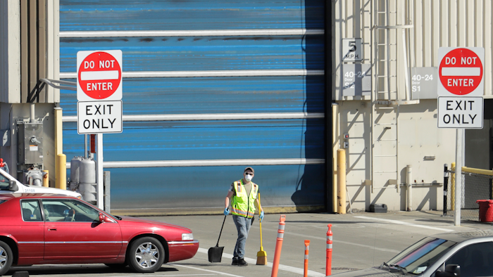 In this April 13, 2020 file photo, a worker wears a mask as he cleans up an area outside an entrance at Boeing Co.'s airplane assembly facility in Everett, Wash., north of Seattle.