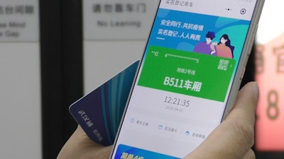 In this April 1, 2020, photo, a passenger holds up a green pass on their phone on a subway train in Wuhan in central China's Hubei province. Green is the 'health code' that says a user is symptom-free and it’s required to board a subway, check into a hotel or just enter Wuhan, the central city of 11 million people where the pandemic began in December.