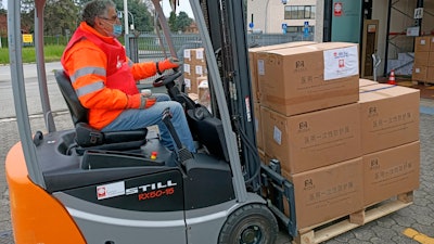 An operator wearing a face mask to protect himself against the spread of Covid-19 stacks boxes of medical supplies from Chinese charity Jinde Charities at the Italian charity Caritas Ambrosiana logistic center in Burago, in Monza Brianza, northern Italy, Wednesday, April 1, 2020.